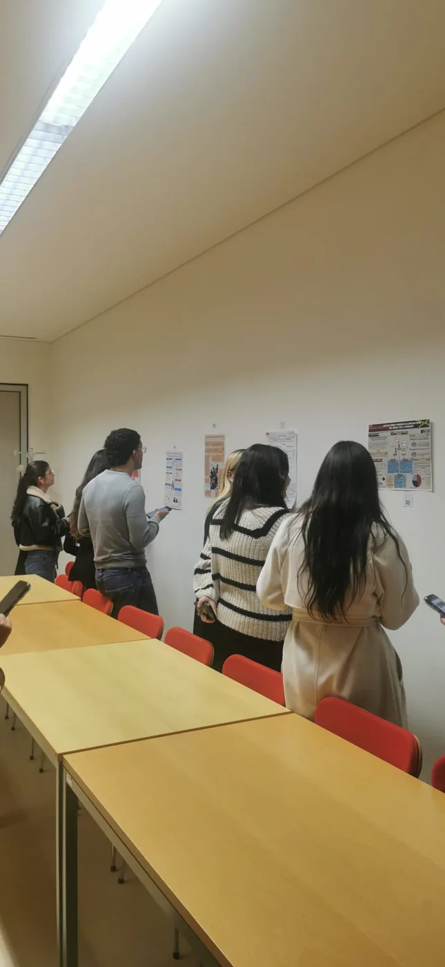 Estudantes observam e discutem pósteres académicos numa atividade de aprendizagem entre pares.
